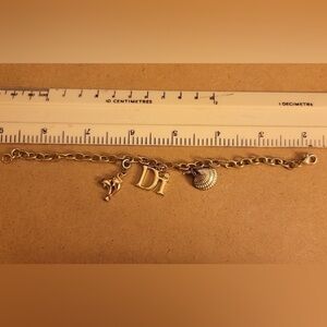 Diamond International golden bracelet with shell and dolphin charm.